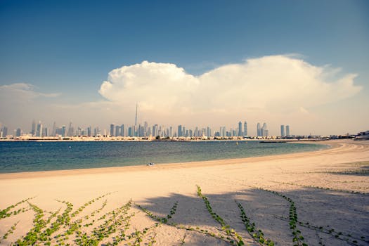 Dubai skyline with Burj Khalifa from a sandy beach under a bright sky.